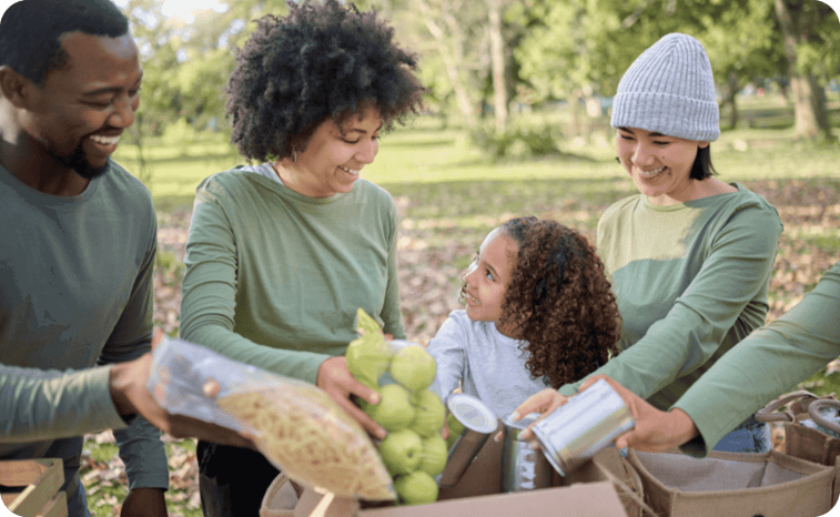 A group of four people and a child sorting food items into boxes outdoors. A group of four people and a child sorting food items into boxes outdoors.